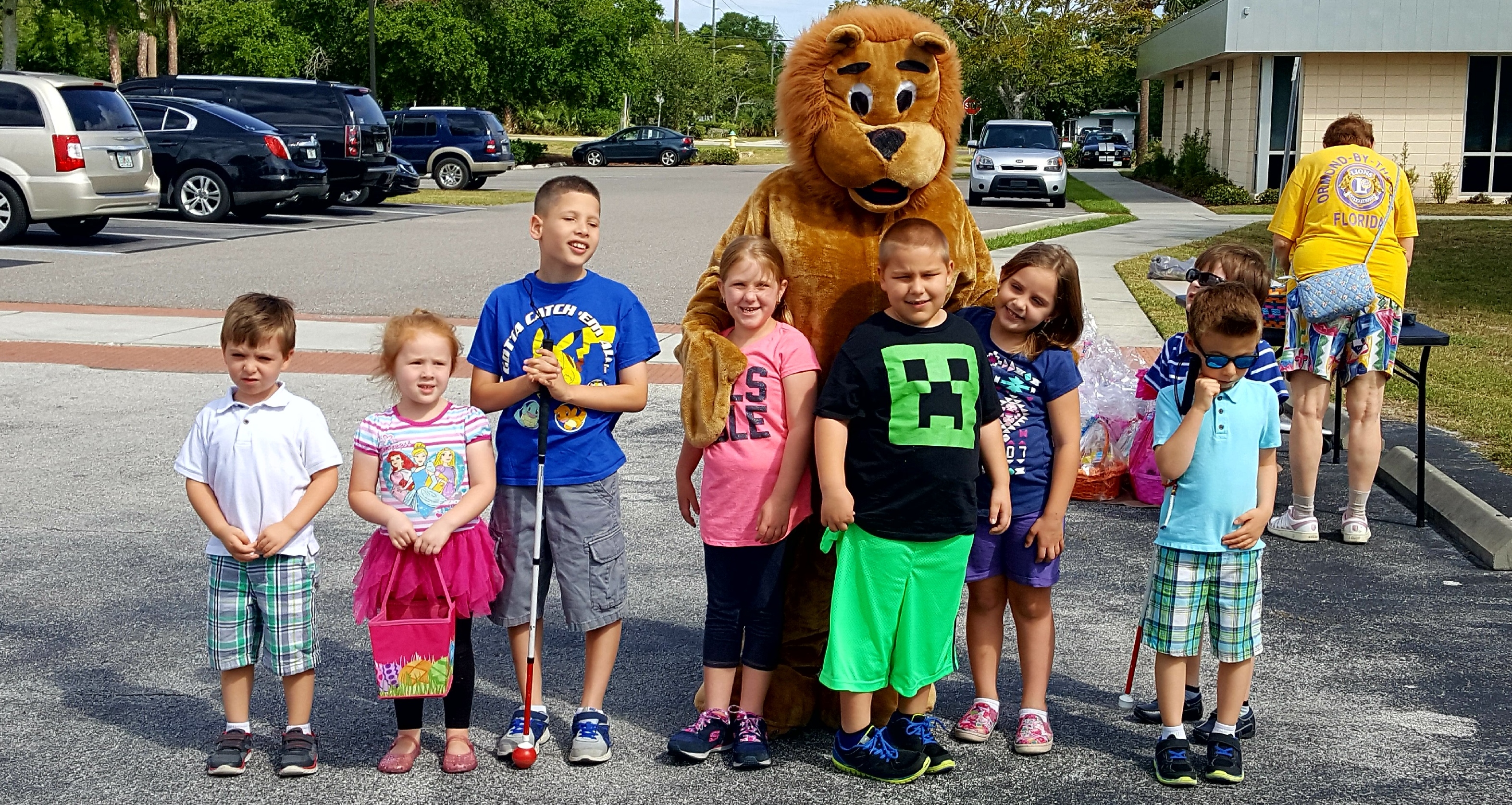 Eight kids under the age of ten  smiling with someone in a lion costume